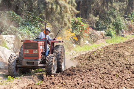 Man preparing the land for harvest with the tractor on the farmの写真素材