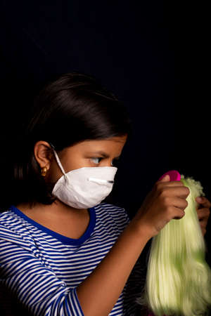 Little girl with medical face mask, playing with her dollの写真素材