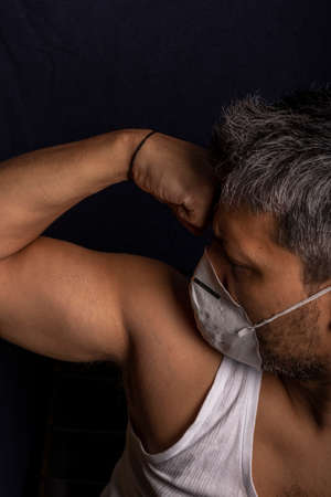 Young man with medical mask demonstrating his strengthの写真素材