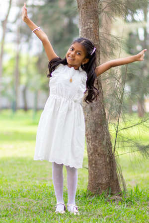 Little girl with white dress and red sweater, very happy and smiling in the forestの写真素材