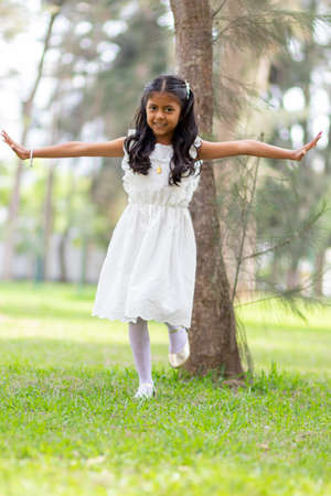 Little girl with white dress and red sweater, very happy and smiling in the forestの写真素材