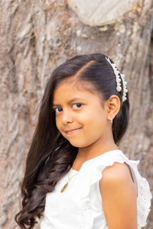 Little girl with white dress and red sweater, very happy and smiling in the forestの写真素材