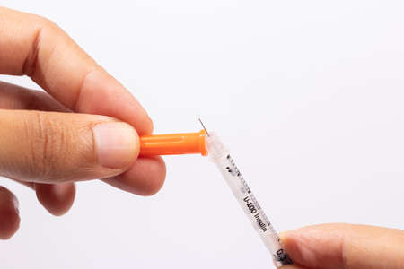 Hand holding an insulin syringe before being usedの写真素材