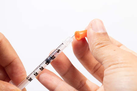 Hand holding an insulin syringe before being usedの写真素材
