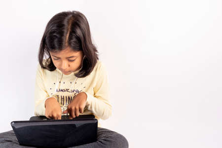 Cute little girl is using her notebook and headphonesの写真素材