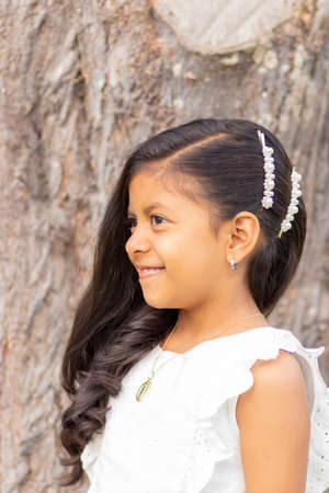 Little girl with white dress and red sweater, very happy and smiling in the forestの写真素材