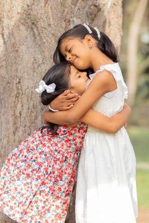 Tender little sisters hugging each other and showing their true loveの写真素材