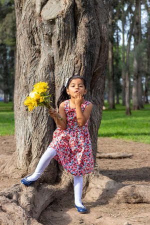 Little girl in dress celebrating in the park with a bouquet of flowers in her handの写真素材