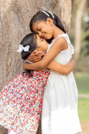 Tender little sisters hugging each other and showing their true loveの写真素材