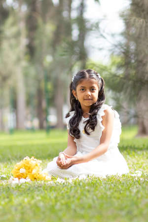 Little girl in white dress and with a cute bouquet of flowers in her handの写真素材