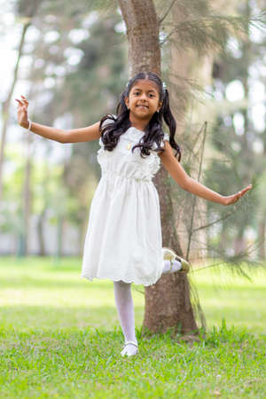 Little girl with white dress and red sweater, very happy and smiling in the forestの写真素材