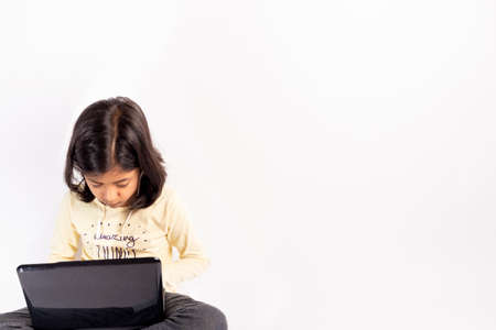 Cute little girl is using her notebook and headphonesの写真素材