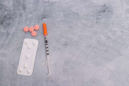 A blister pack of pills and a syringe on a marbled gray backgroundの写真素材