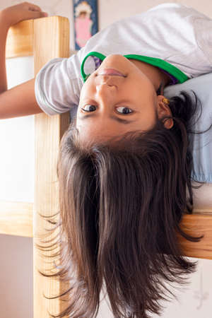 A girl is upside down looking down from the top of her bunkの写真素材