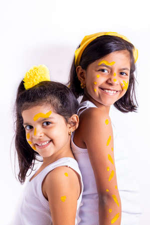 Two little girl, with her face painted to celebrate the yellow dayの写真素材