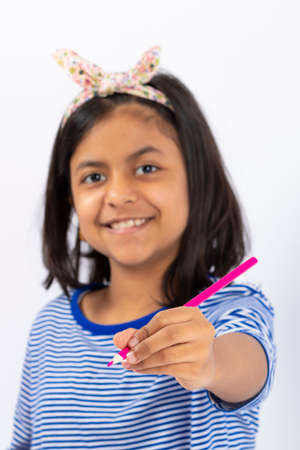 Cute left-handed girl is writing with a pencil in her notebook.の写真素材