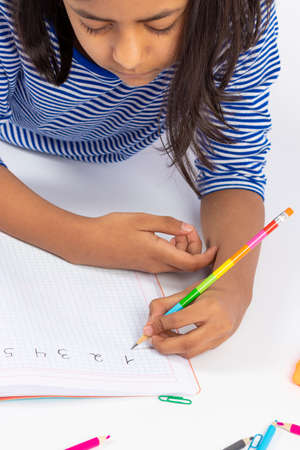 Cute left-handed girl is writing with a pencil in her notebook.の写真素材