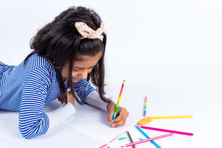Cute left-handed girl is writing with a pencil in her notebook.の写真素材