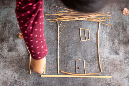 Little girl making a house with sprigs of plants
