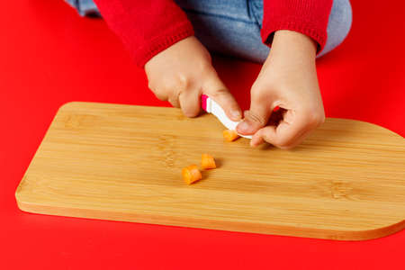 Little child hands cutting baby carrots on tableの写真素材