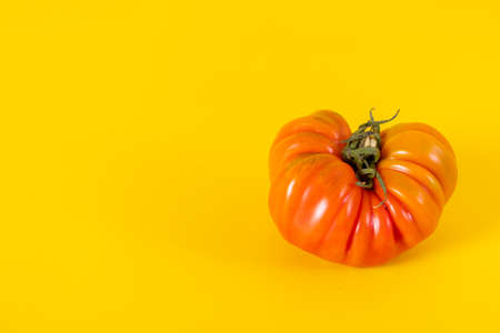 View of beautiful red heirloom tomato on yellow background