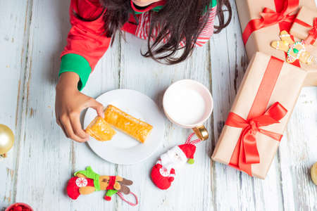 Little sisters eating cookies with milk on Christmas dayの写真素材
