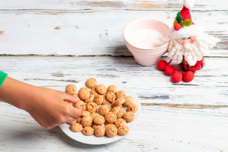 Cute little girl is playing with Santa's cookies and milk at Christmasの写真素材