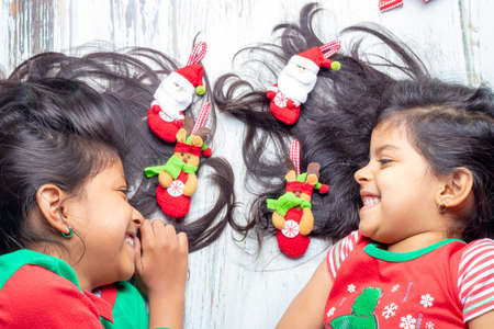 Smiling sisters decorating their hair with Christmas decorationsの写真素材