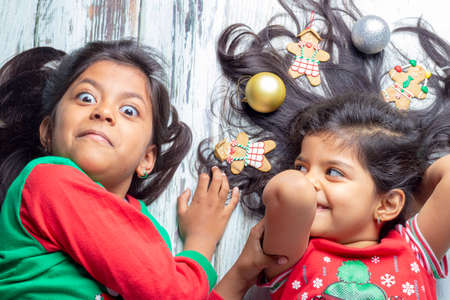 Smiling sisters decorating their hair with Christmas decorationsの写真素材