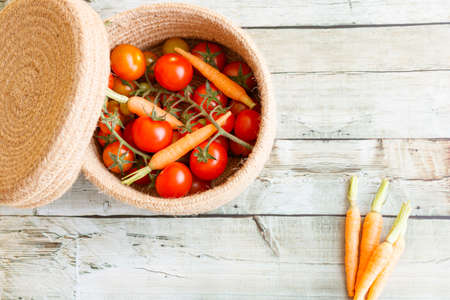 Basket with a variety of baby carrots and tomatoes, including: Cherry, Heirloom and Zebra.の写真素材