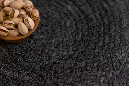 Raw organic pistachio nuts presented on wooden bowl