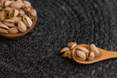 Raw organic pistachio nuts laid out on wooden spoonの写真素材