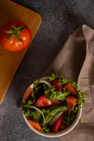 Tomatoes in salad inside a white bowl on grayish backgroundの写真素材
