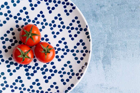 Cherry tomatoes on blue dotted plateの写真素材