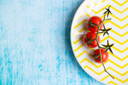 Cherry tomatoes on yellow striped plateの写真素材