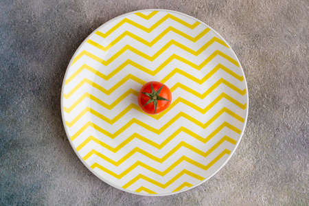 Cherry tomatoes on yellow striped plateの写真素材