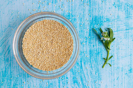 Raw quinoa grains inside transparent bowl, on blue tableの写真素材