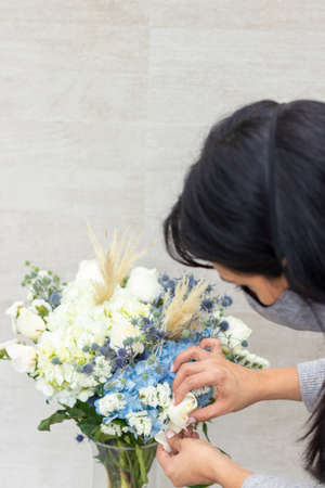 Cute woman florist is making a bouquet of white roses and hydrangeasの写真素材