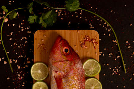 Still life with raw fresh fish on a table with seasonings and lemonの写真素材