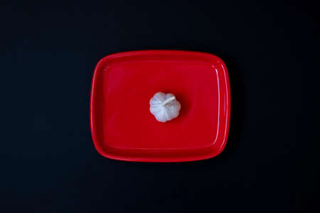 Garlic head in a red bowl on dark backgroundの写真素材