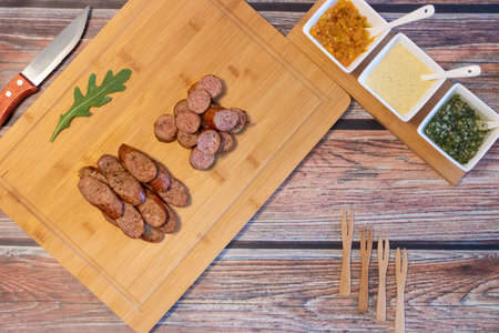 Grilled sausages with spices and sauces on the tableの写真素材
