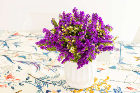 Cute flower arrangement with purple statice, decorating the dinner tableの写真素材