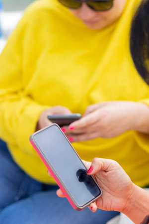 Sharing a meeting of friends together with social networks on the smartphone. Women checking their smartphoneの写真素材