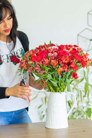 Cute woman using scissors to cut the stems of flower bouquetsの写真素材