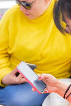 Sharing a meeting of friends together with social networks on the smartphone. Women checking their smartphoneの写真素材