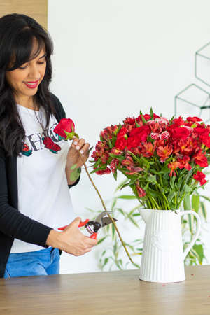 Cute woman using scissors to cut the stems of flower bouquetsの写真素材