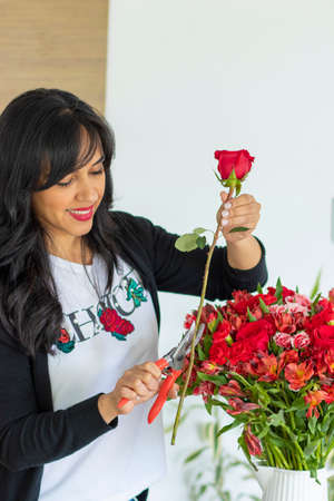 Cute woman using scissors to cut the stems of flower bouquetsの写真素材