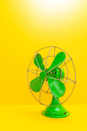 Old green electric fan on yellow backgroundの写真素材