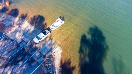 Pickup truck pulling boat and trailer out of the water at the shore of a lake.の写真素材