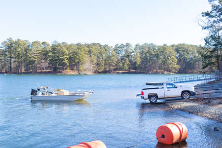 Pickup truck pulling boat and trailer out of the water at the shore of a lake.の写真素材